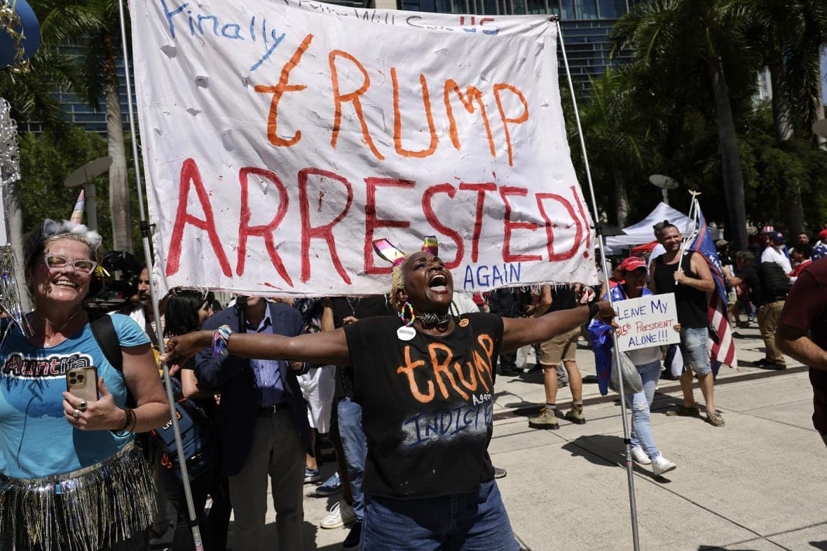 Trump opponent Nabine Seiler holds a sign that reads “Finally Trump Arrested Again”