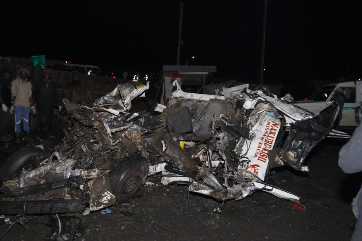People stand near the wreckage of vehicles after a fatal accident in Kenya