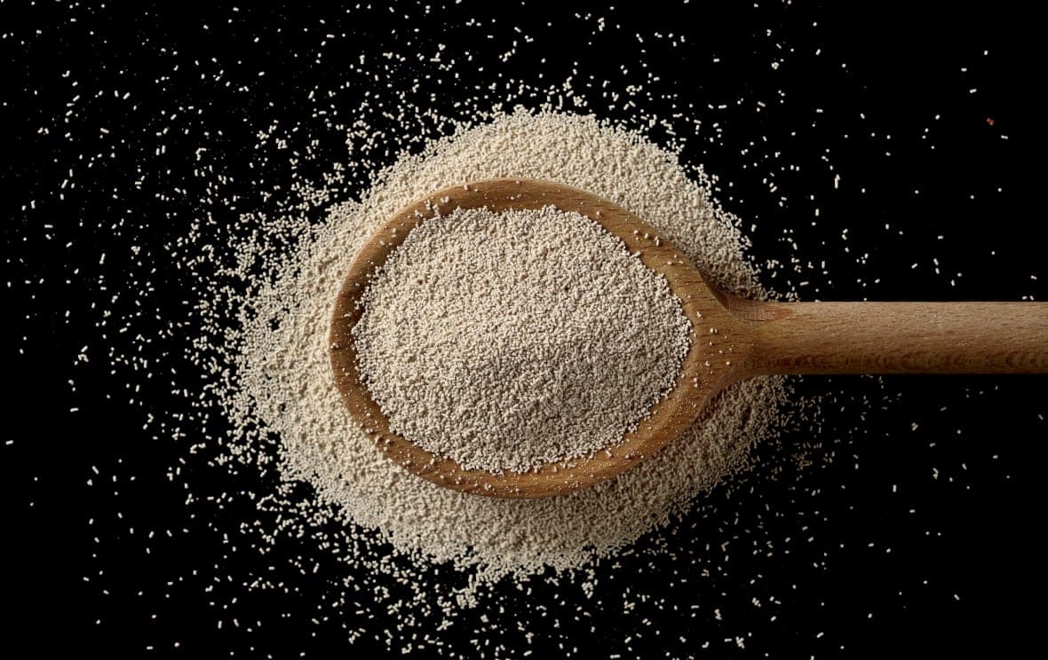 A wooden spoon overflowing with yeast