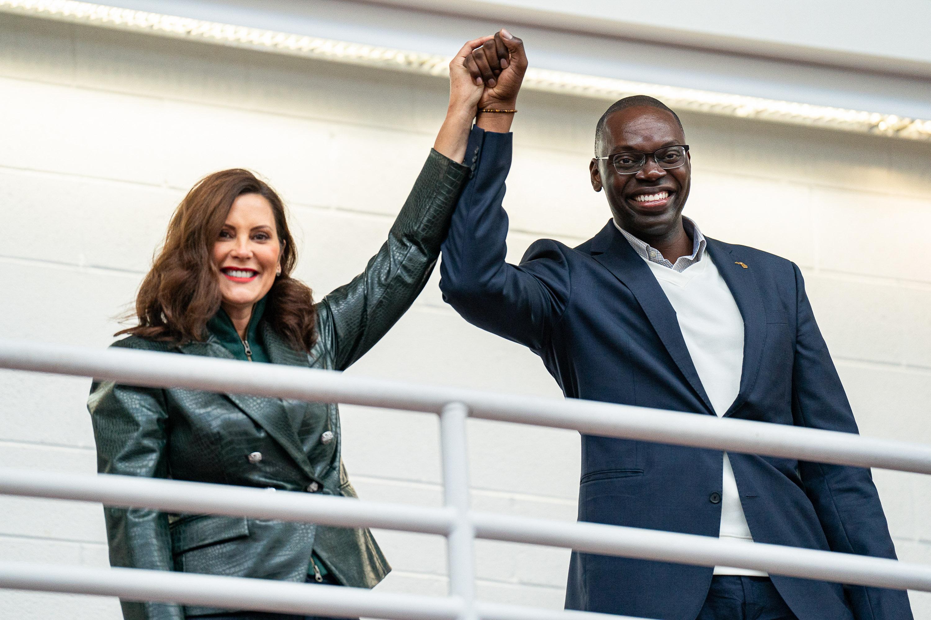 Michigan Governor Gretchen Whitmer and Lieutenant Governor Garlin Gilchrist raise their hands in victory on a balcony