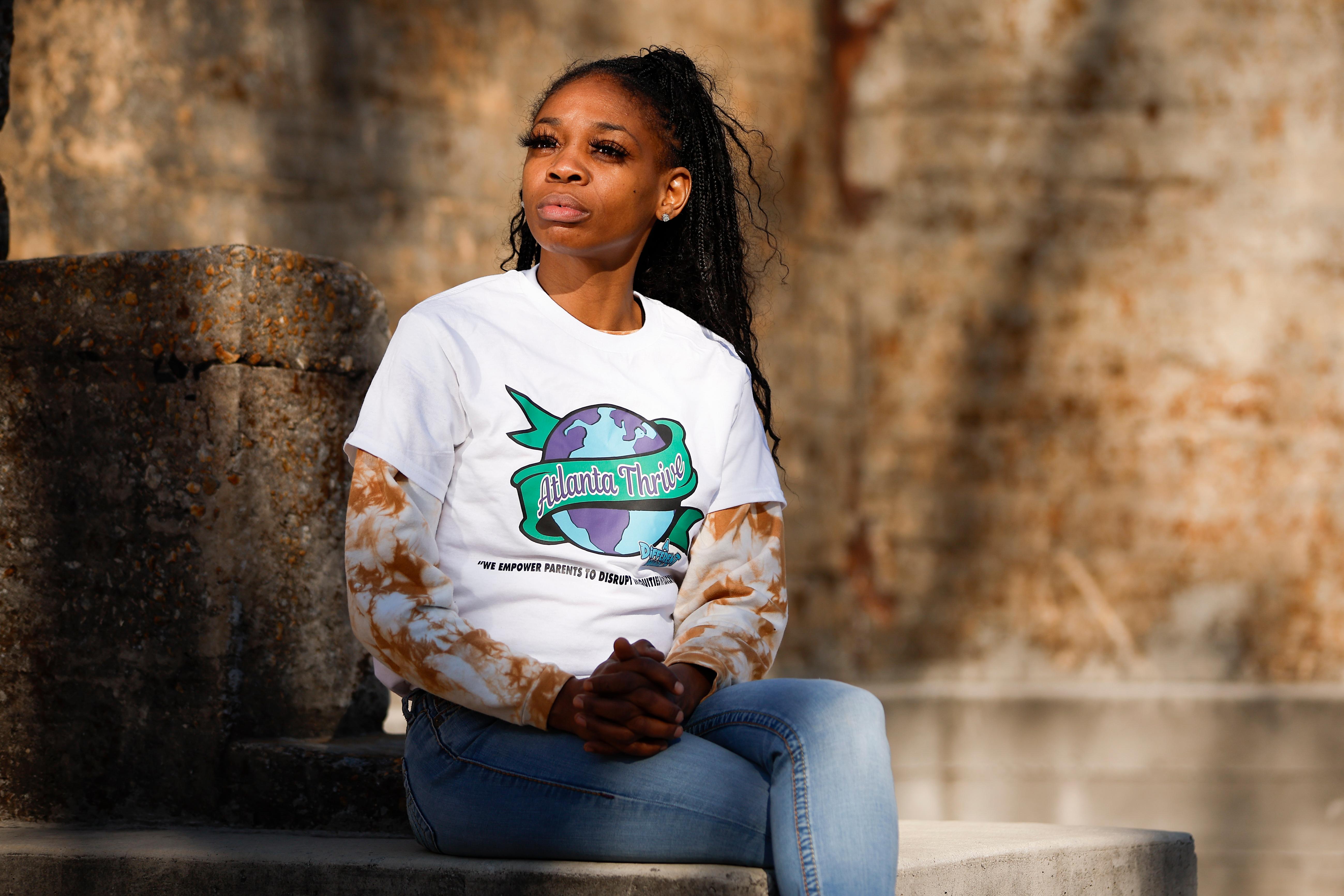 Kimberly Dukes wearing a white "Atlanta Thrives" T-shirt and blue jeans sitting