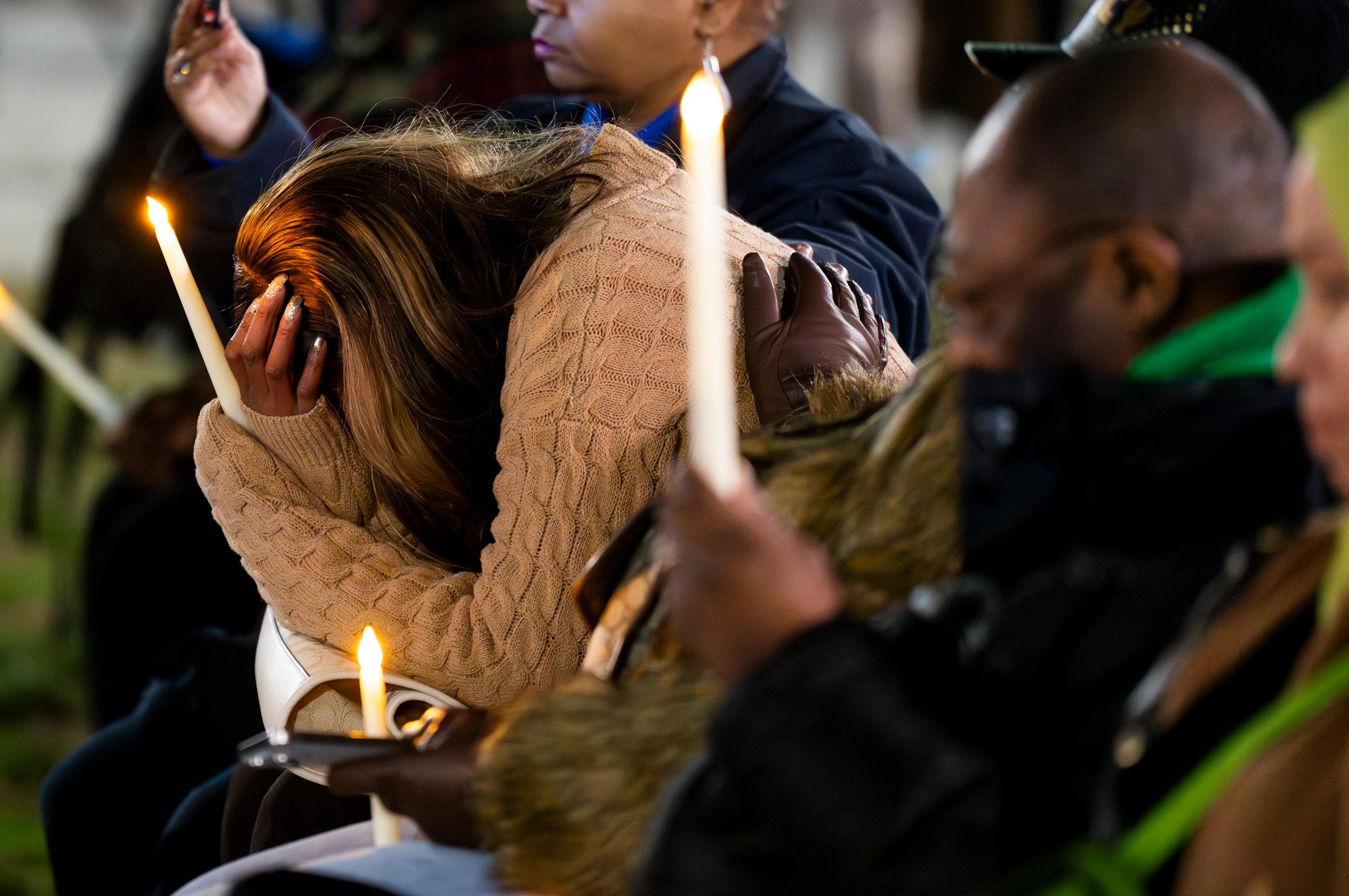 Donna Bruce holds her hand in her hands and cries during during a vigil for the homicide victims of 2023