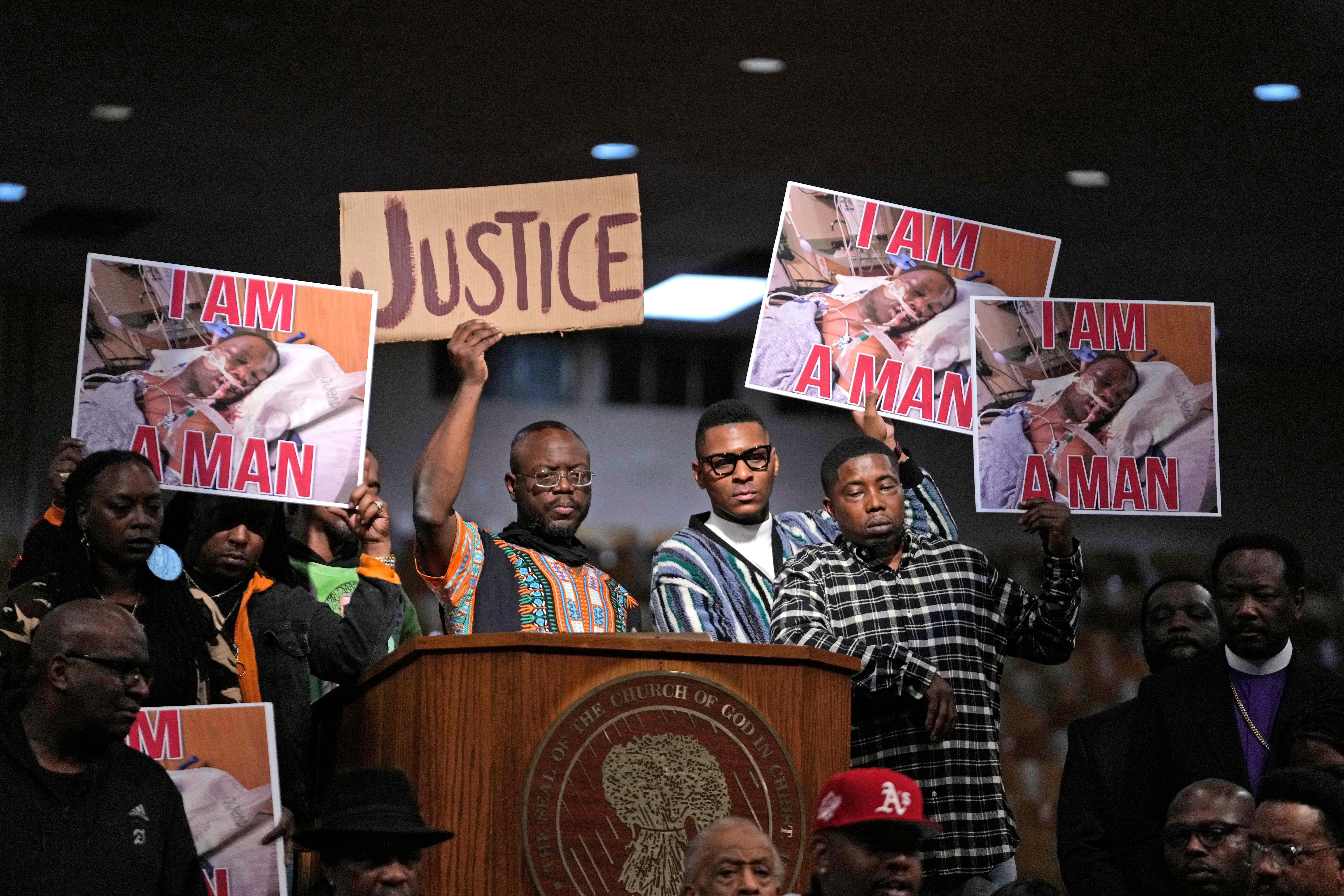 People hold signs during a news conference discussing the death of Tyre Nichols