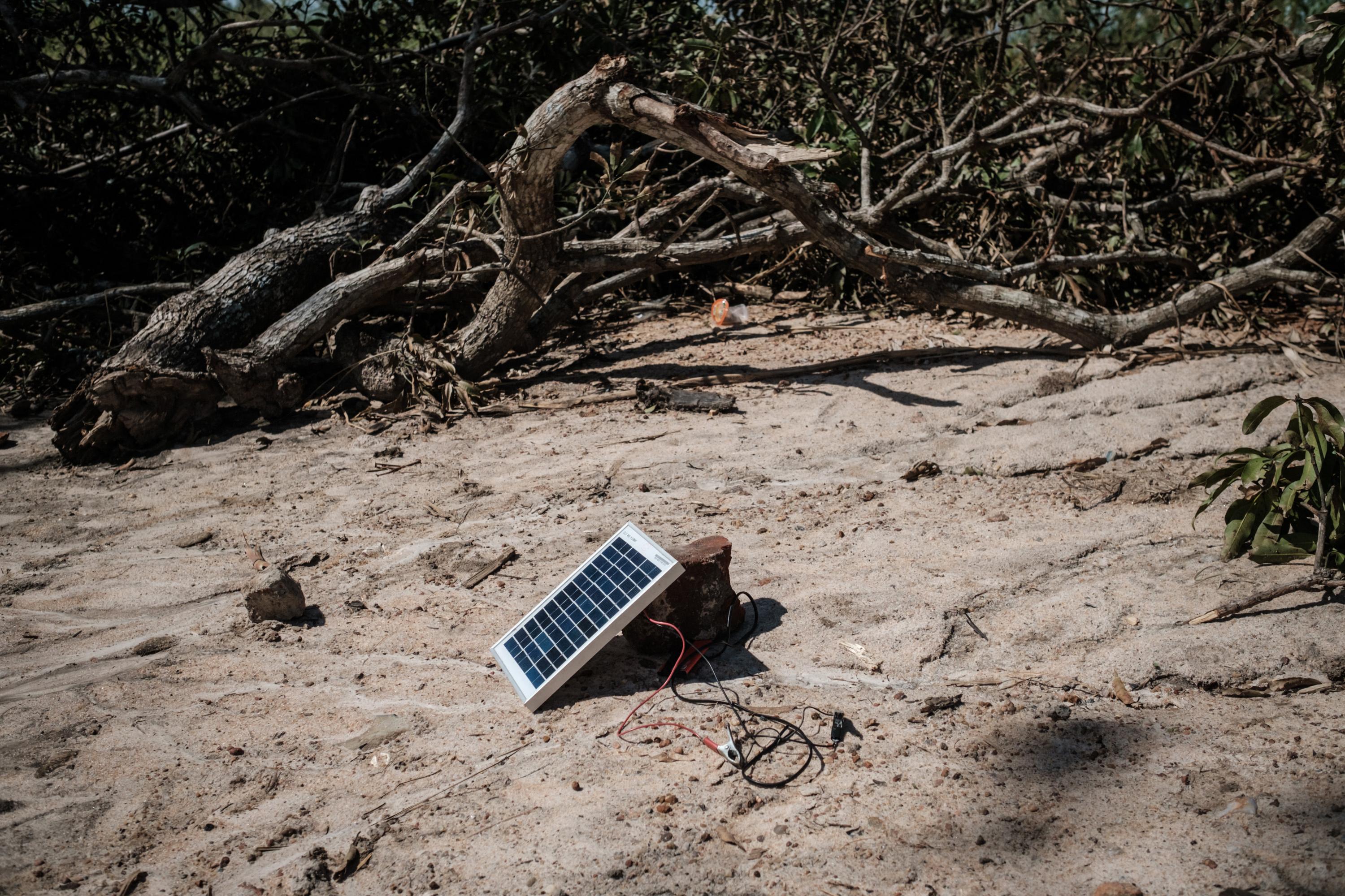 A solar charger is seen beside trees destroyed when a deadly cyclone hit Tica, Mozambique