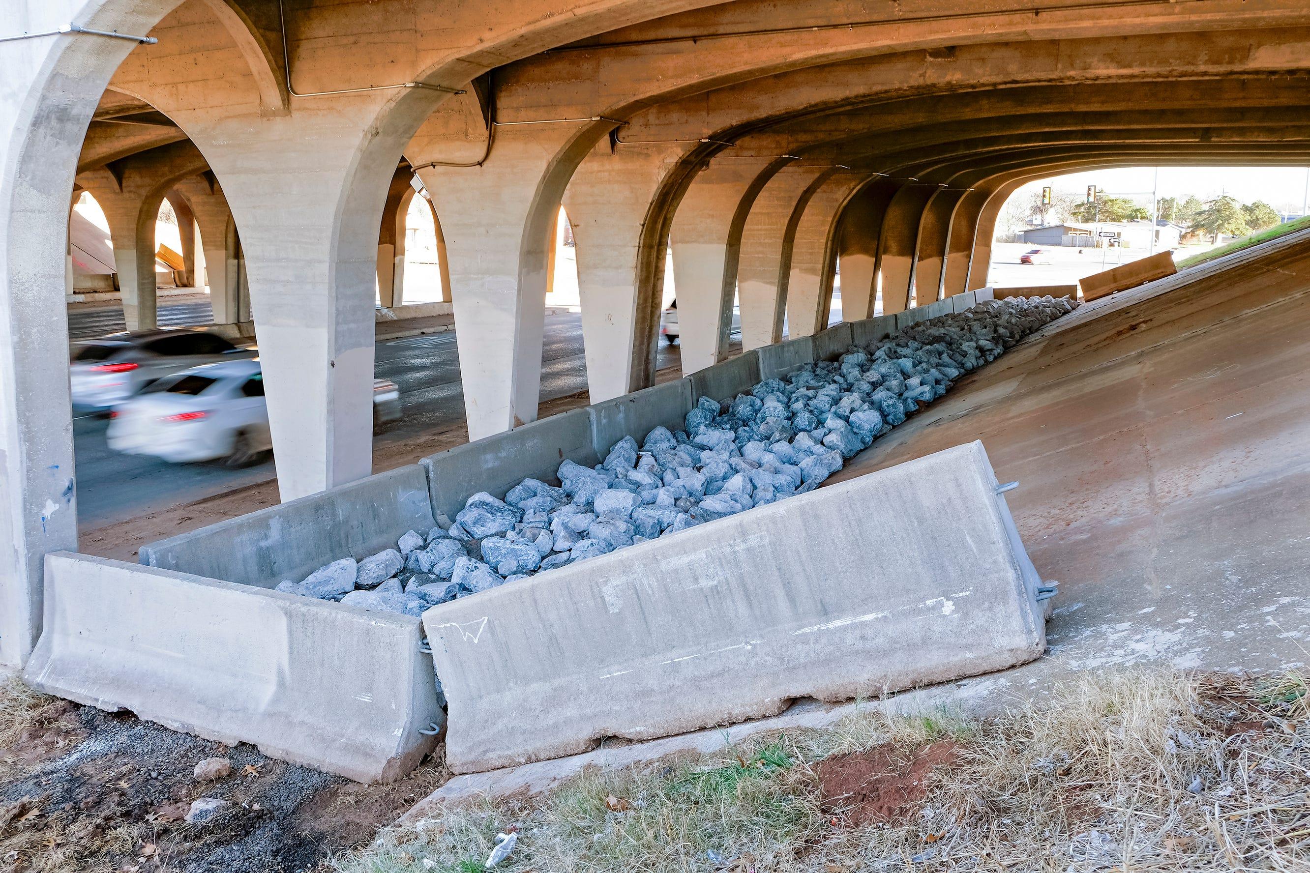 Cement barriers and large bluish rocks obstruct the area beneath a bridge In Oklahoma