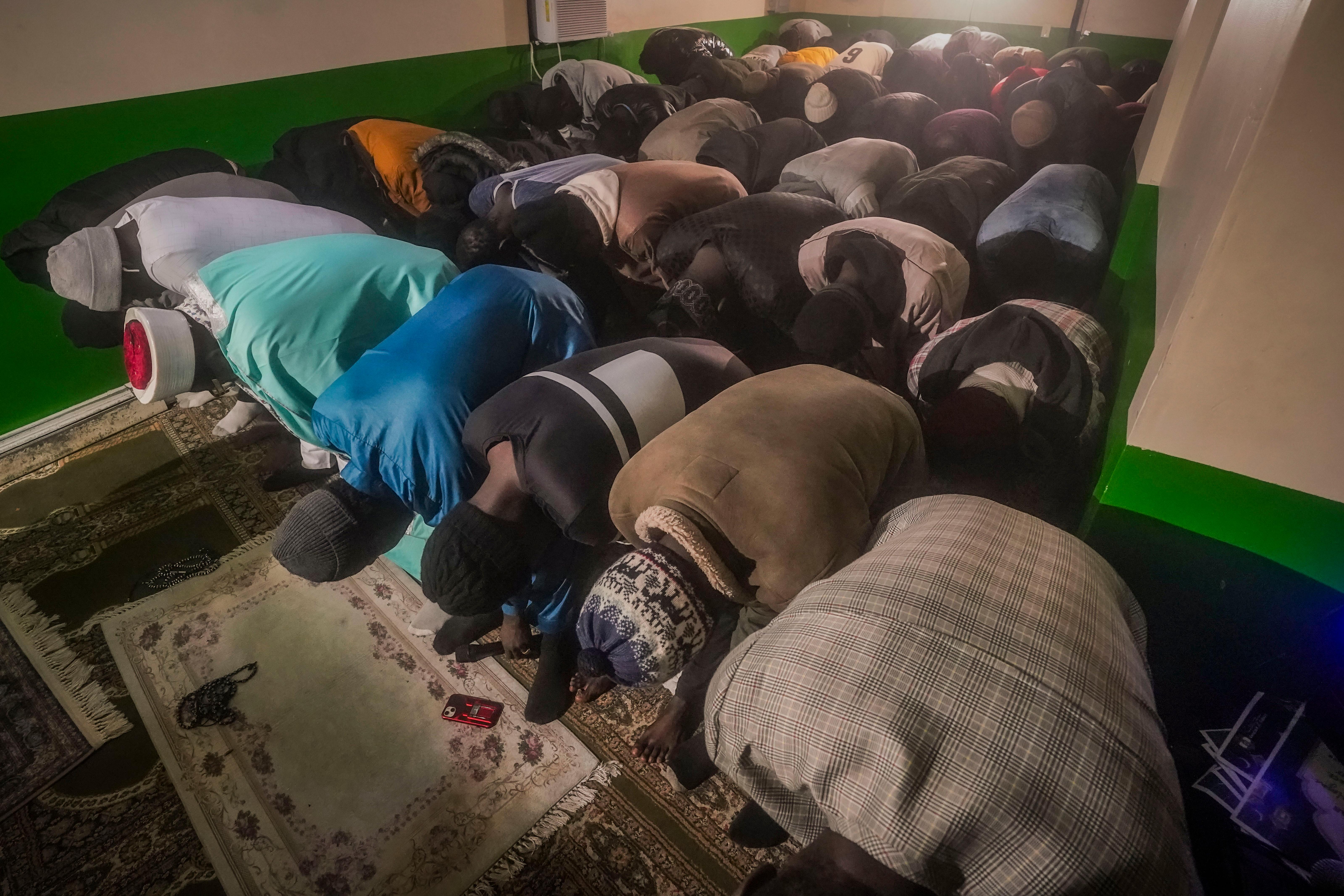 Imam Omar Niass, third from left top, lead evening prayers for African migrants