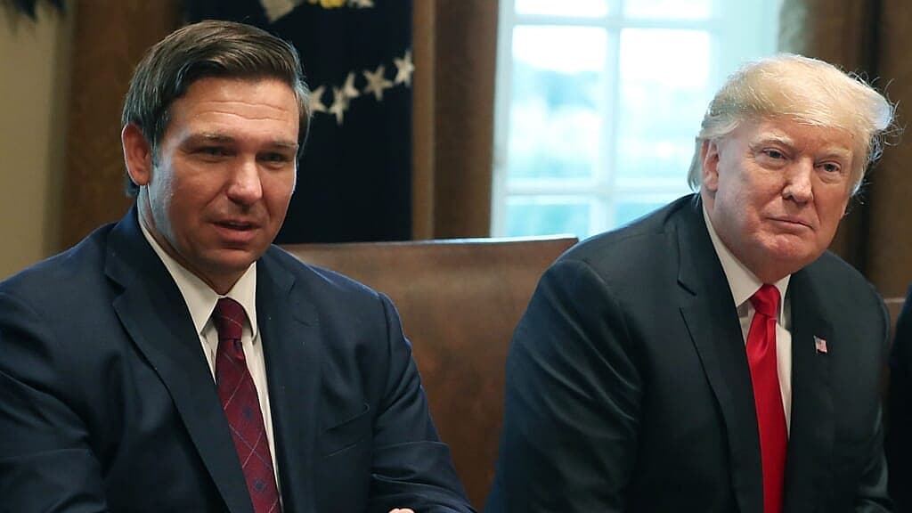 Florida Governor Ron DeSantis and former President Donald Trump, both wearing navy jackets and red ties