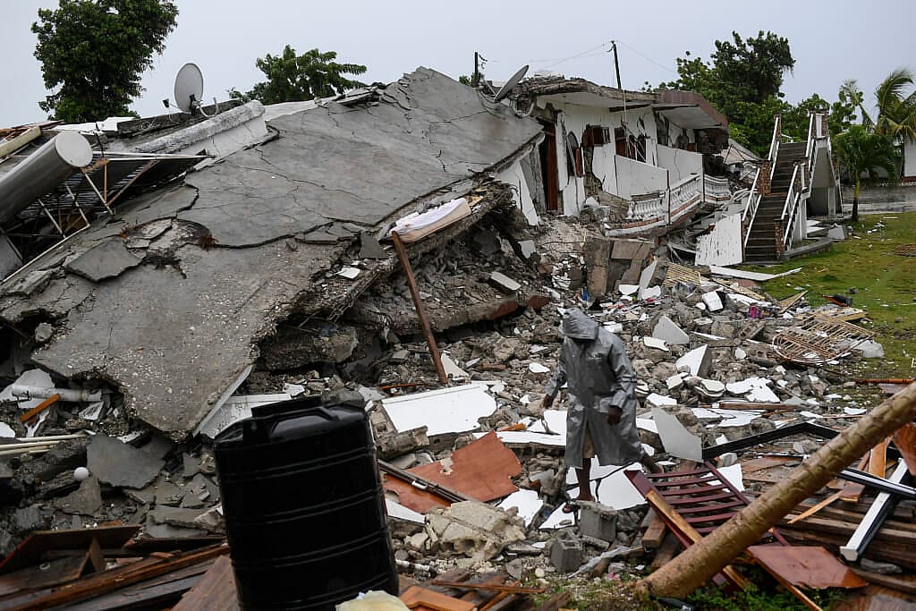 A man walks on the rubble of a collapsed hotel
