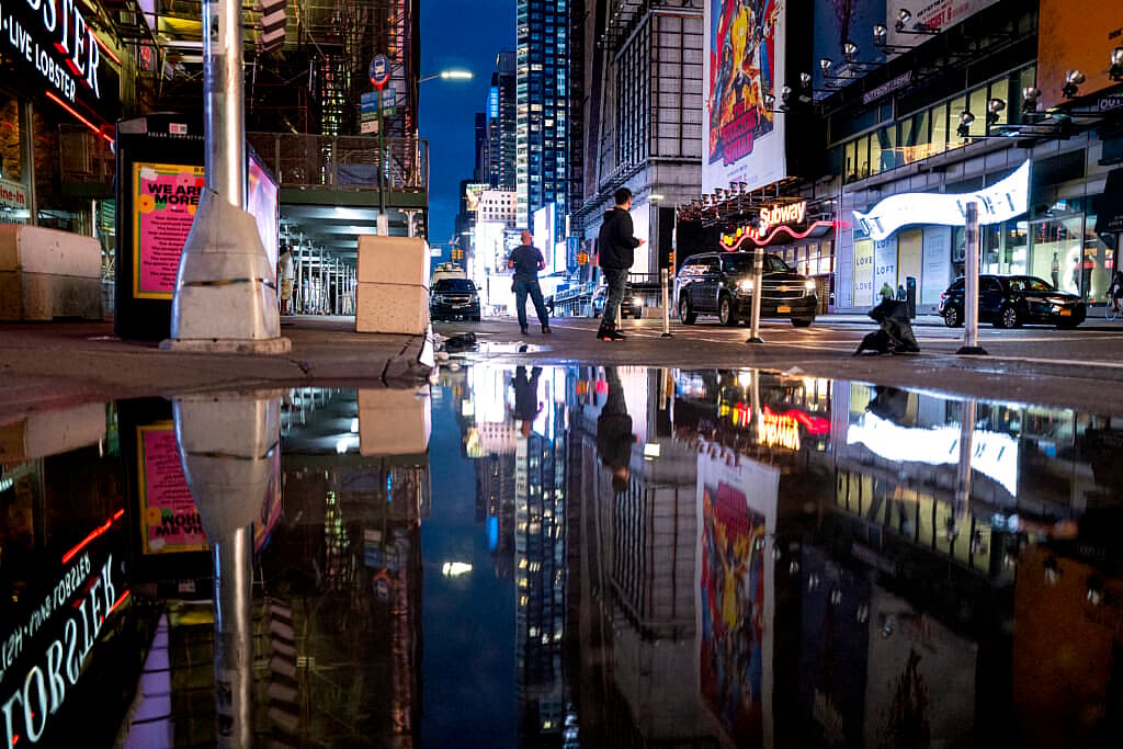 The lights of Times Square in New York reflected in standing water