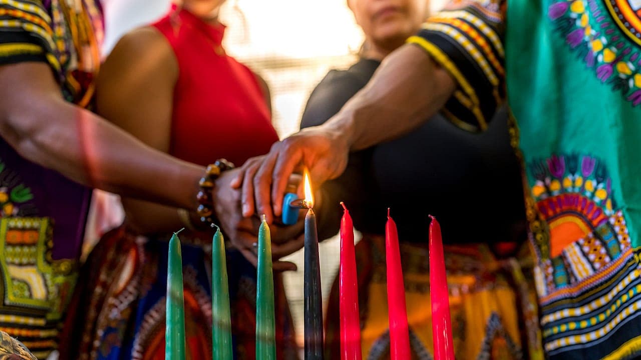 A family lighting the black Kwanzaa candle