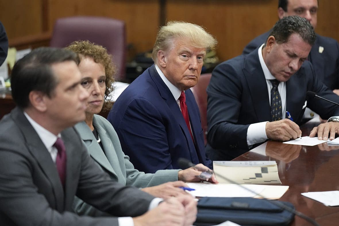 Former President Donald Trump sits at the defense table with his defense team