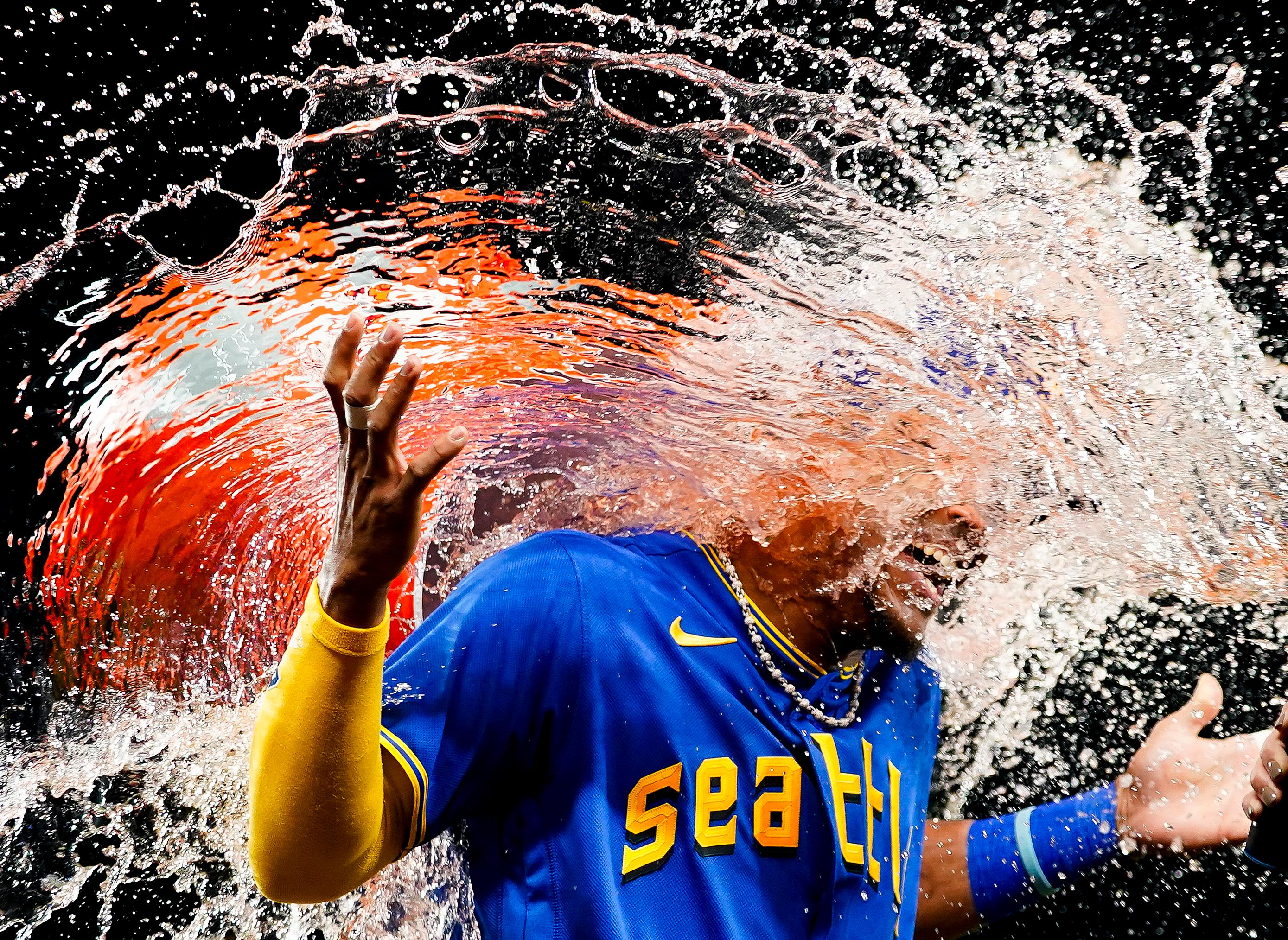 Seattle Mariners center fielder Julio Rodríguez laughs as teammate Teoscar Hernández douses him