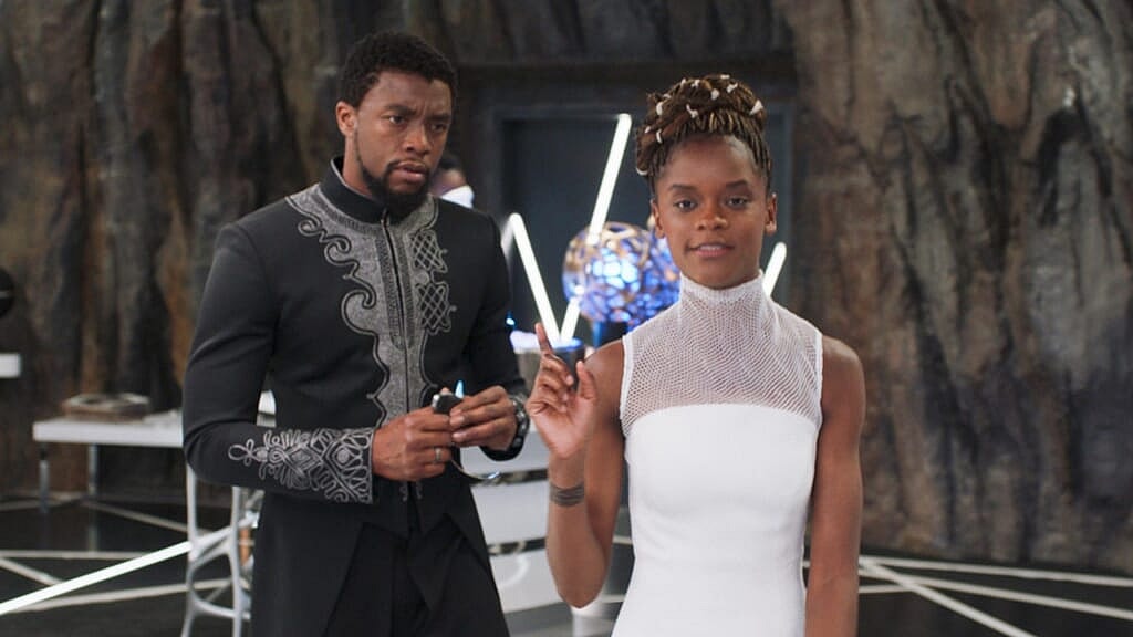 Actors Chadwick Boseman, in a black and gray robe, and Letitia Wright, in a white holding a wand