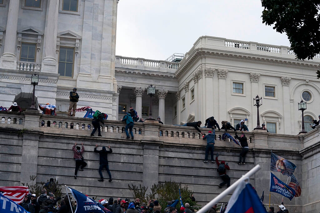 Supporters of former President Donald Trump climb the West wall of the the U.S. Capitol