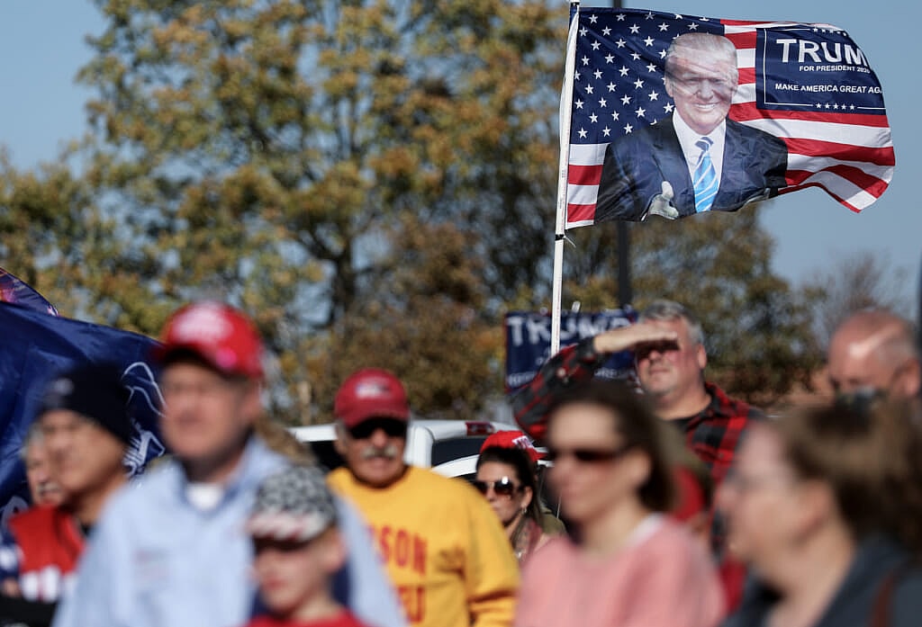 A group of people with a Donald Trump flag