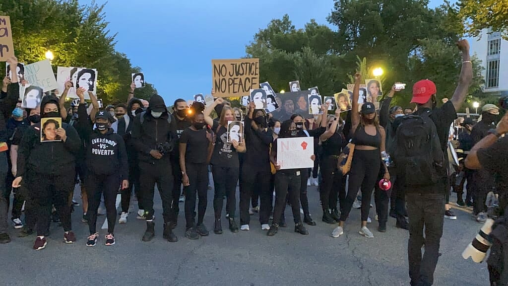 A group of demonstrators wearing black stand in the street