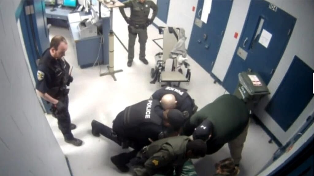 Police officers restrain a man