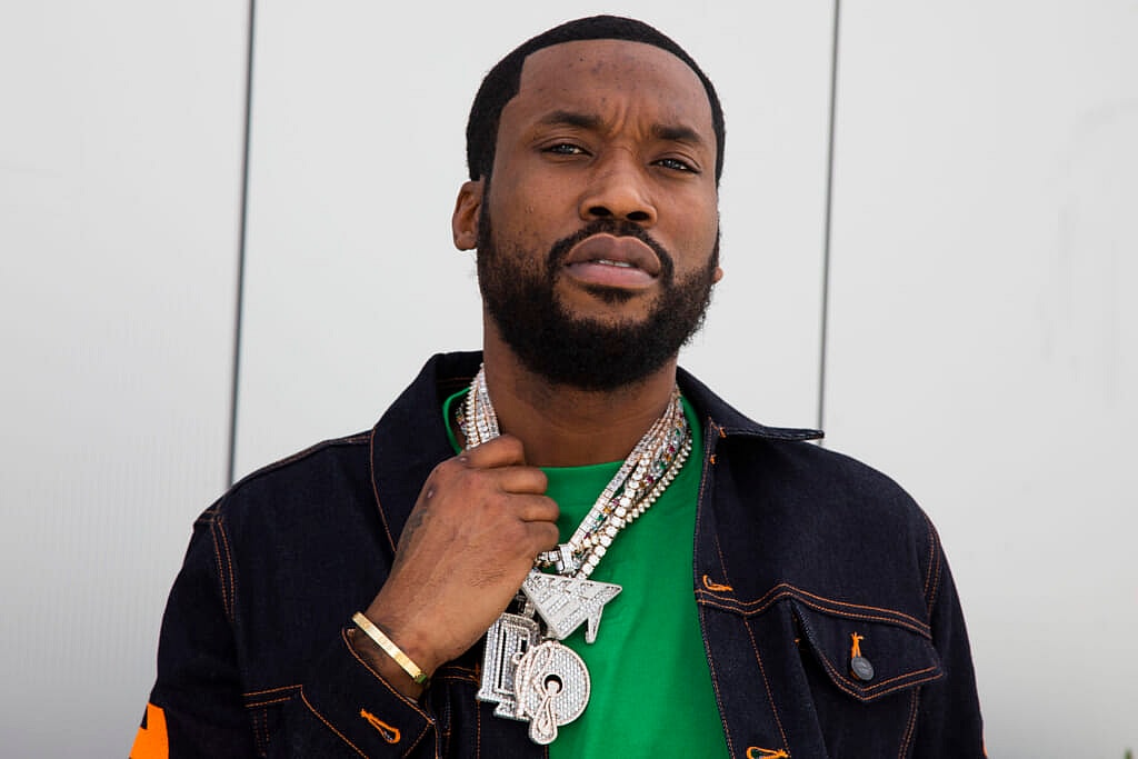 Rapper Meek Mill wearing a silver necklace, black jacket and green shirt