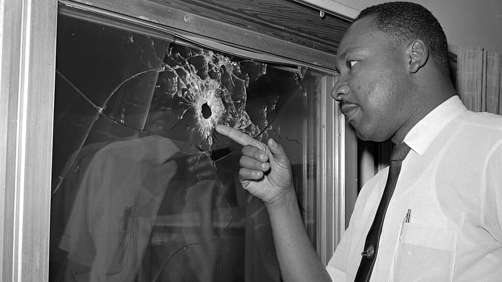 Dr. Martin Luther King Jr. points at a window with a bullet hole