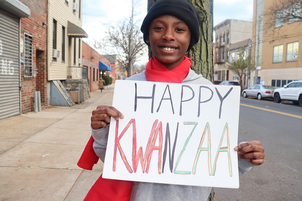 A person holds a "Happy Kwanzaa" sign