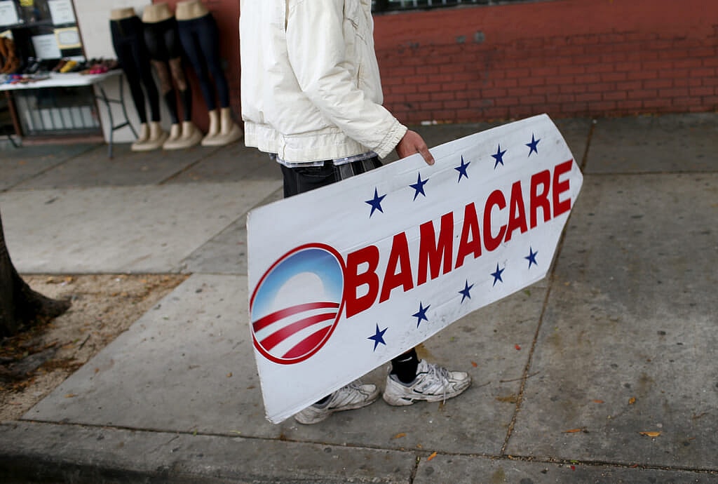 Pedro Rojas holds a sign directing people to an insurance company where they can sign up for the Affordable Care Act