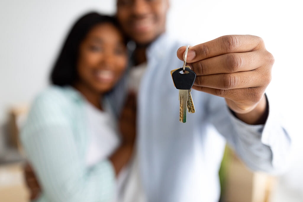 An embracing couple holds up a set of house keys