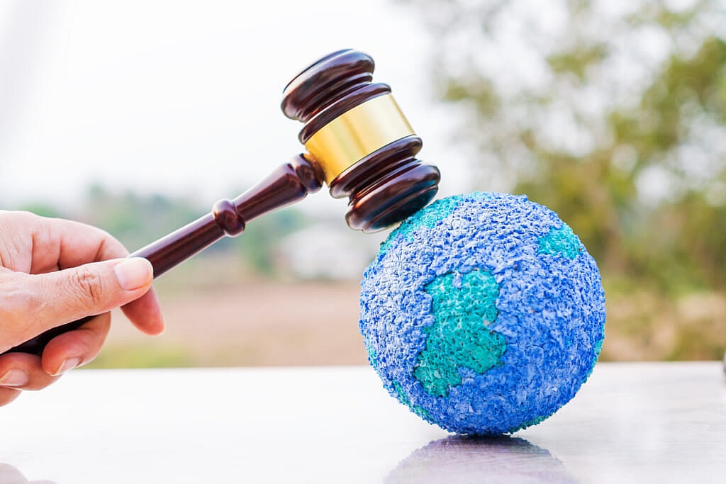 A hand holds a gavel tapping a globe