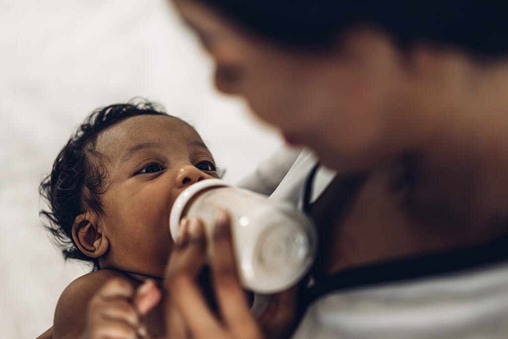 A woman gives a baby a bottle