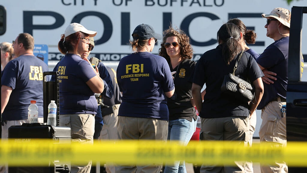 Several FBI agents stand behind crime scene tape