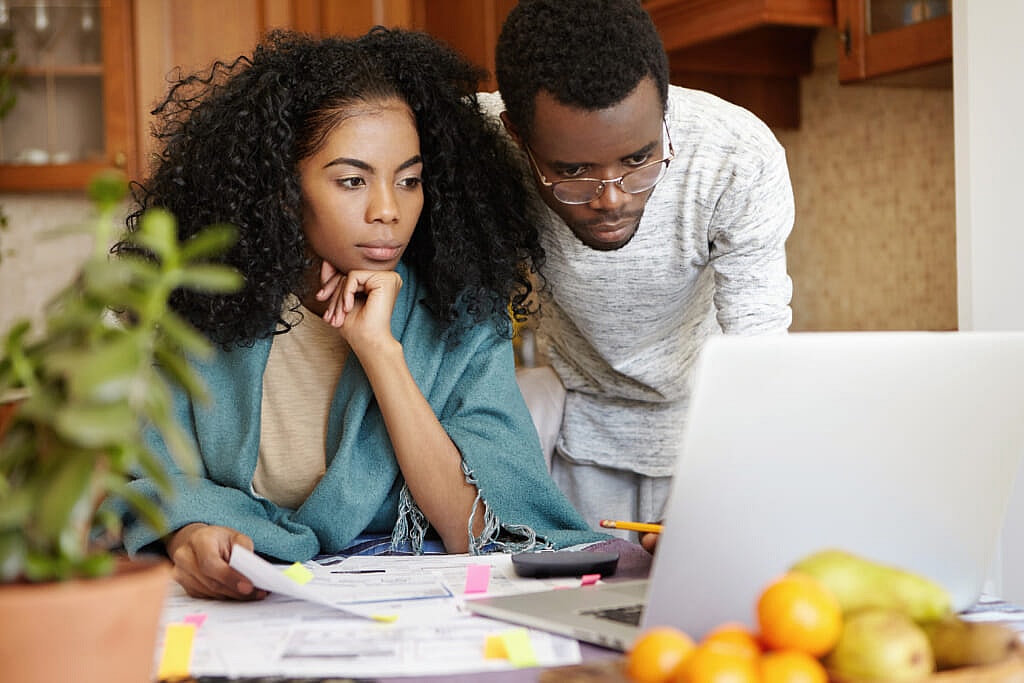 A couple looking at a laptop and reviewing papers