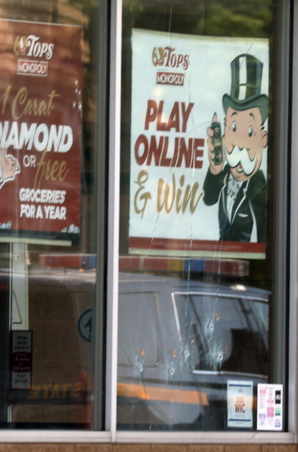 Five bullet holes can be seen in the lower part of the window below the Play Online sign at the Tops Friendly Market