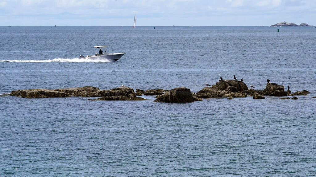 A boat glides past a rocky outcrop off Mingo Beach