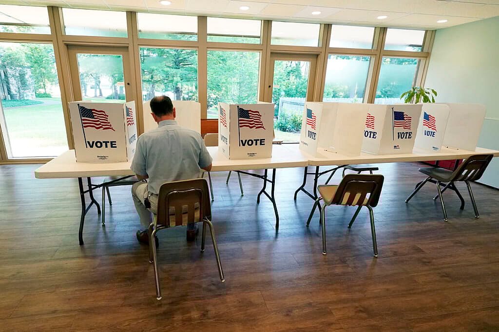 A man sits at a poll kiosk table