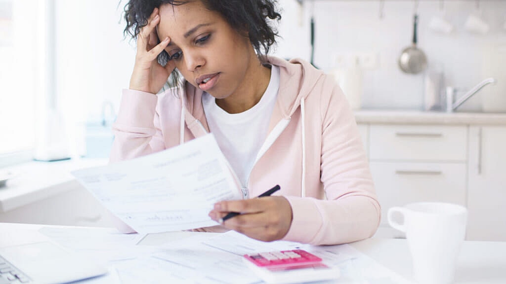 A woman holds her head while looking at paperwork