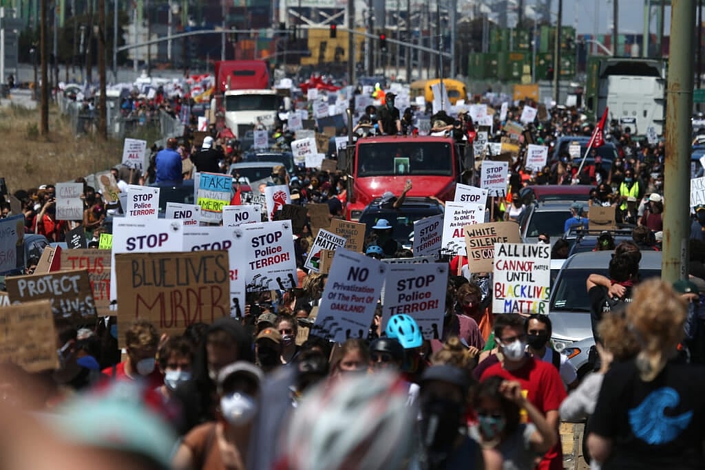 A group of demonstrators carrying signs protesting police violence.