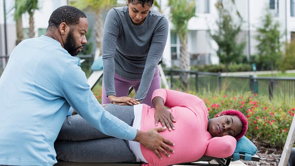 Two people assisting a pregnant woman