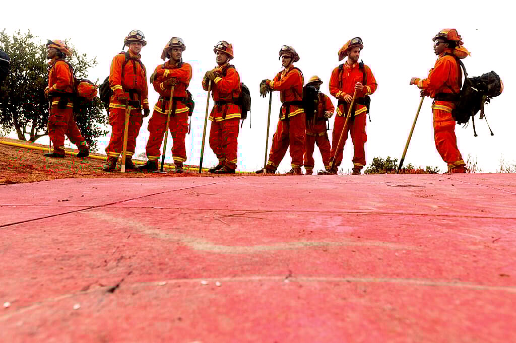 Inmate firefighters in bright orange fire gear prepare to take on the River Fire