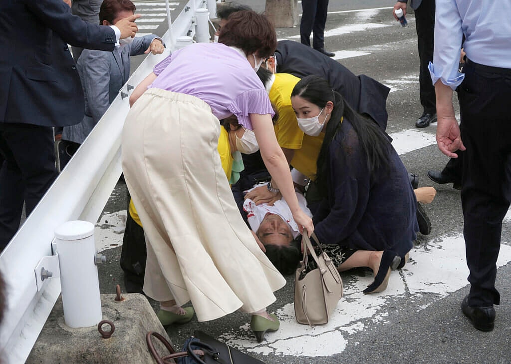 Japan’s former Prime Minister Shinzo Abe, center, lying on the ground