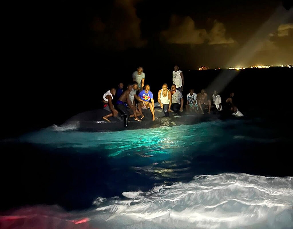 Survivors sit on a capsized boat as they are about to be rescued near New Providence in the Bahamas