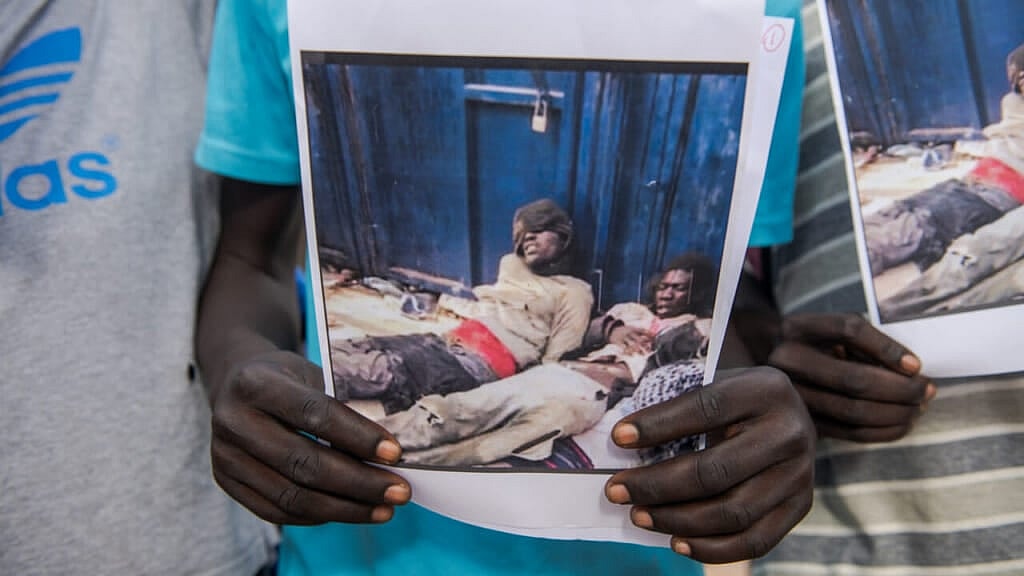 A protester holds images of the violence immigrants suffered