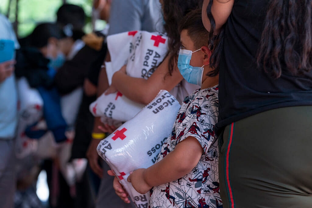 Children who arrived off a bus from Arizona with their families hold blankets from the American Red Cross