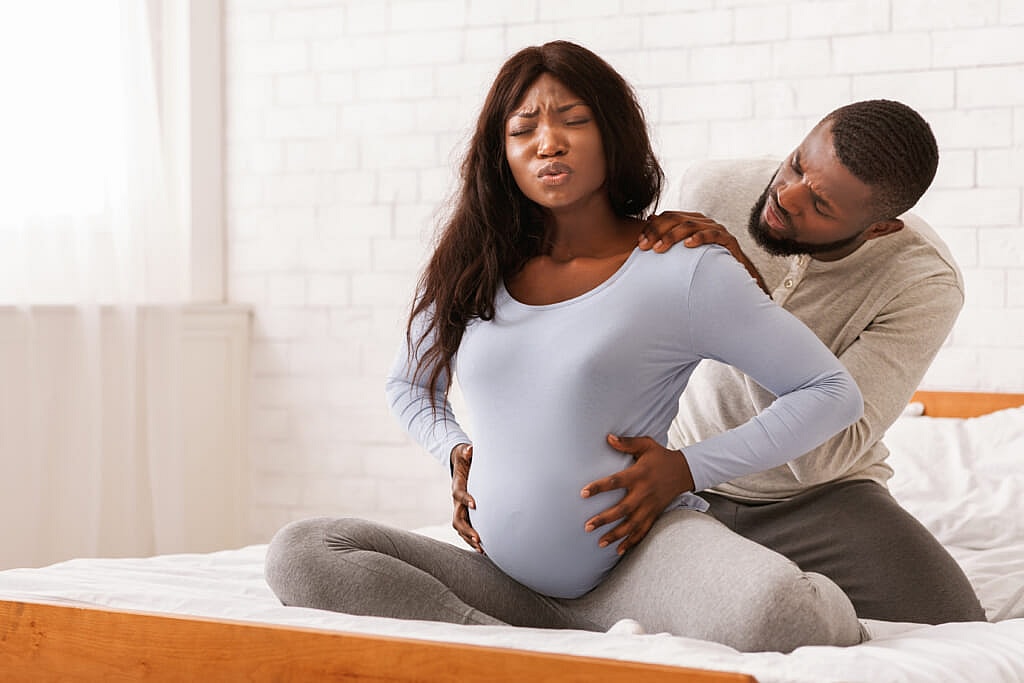 A man with his hands on the shoulders of a pregnant woman