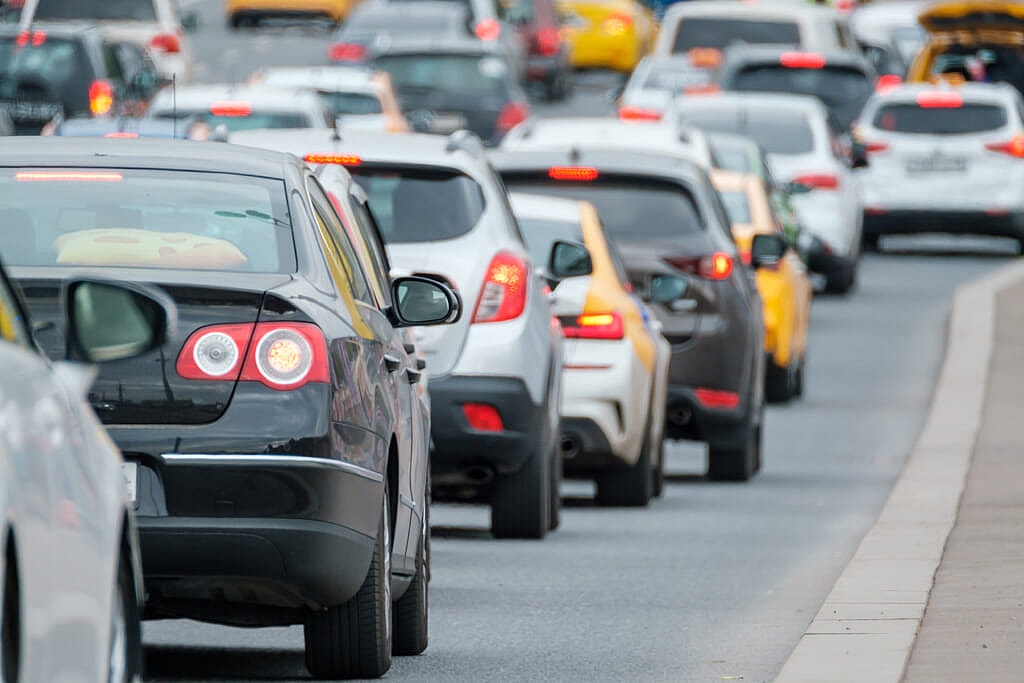 Many modern vehicles driving in traffic jam on busy city street in daytime
