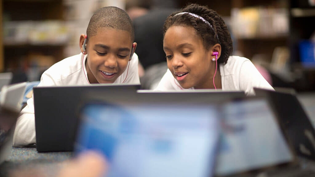 Two children use laptops