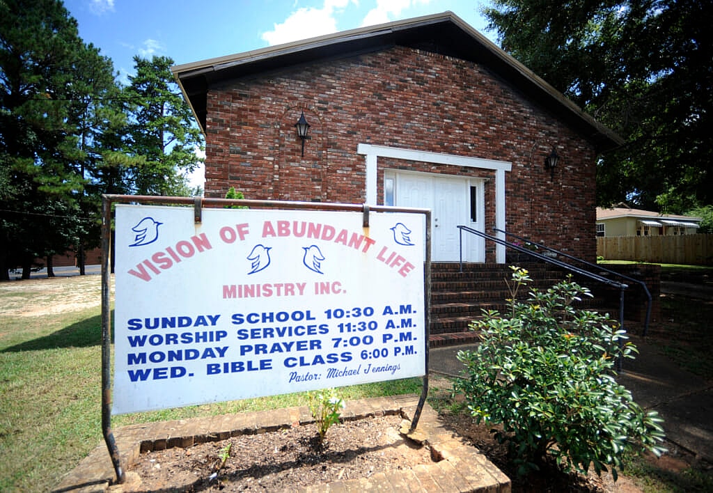 A brick building with white double doors and a sign reading "Vision of Abundant Life Ministry, Inc."