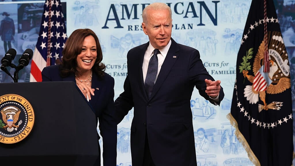 Vice President Kamala Harris and President Joe Biden at a podium, both wearing black jackets