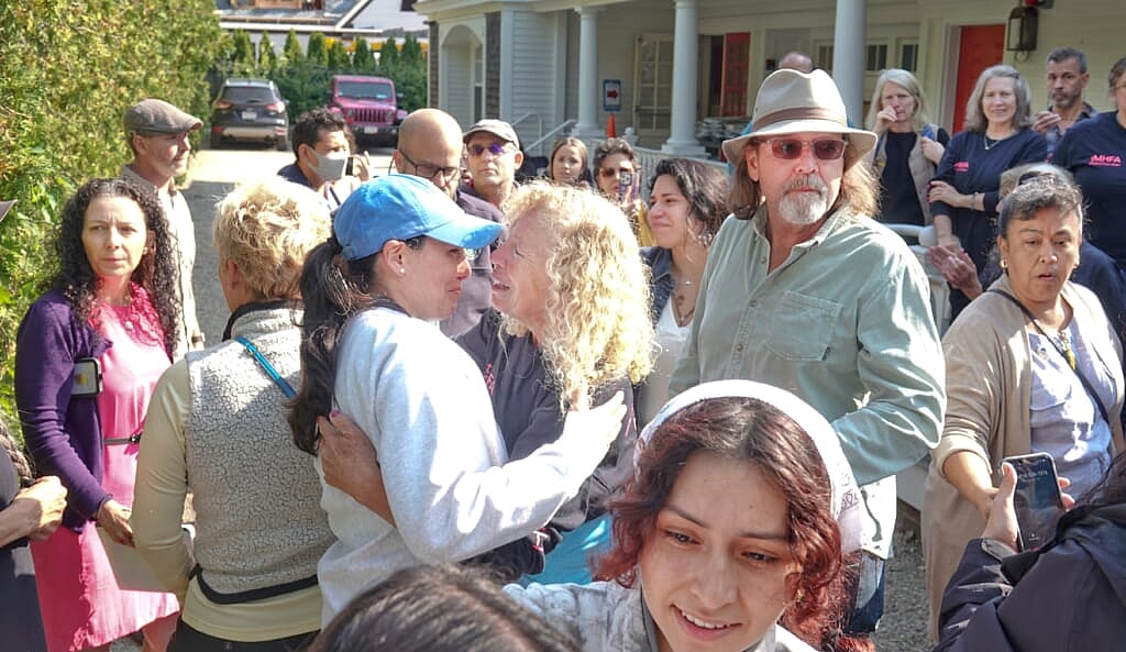 Lisa Belcastaro (center) has an emotional moment as immigrants and volunteers prepare to depart
