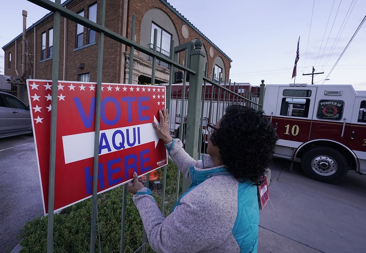 Election worker Ramona Ortiz places a sign outside a polling station