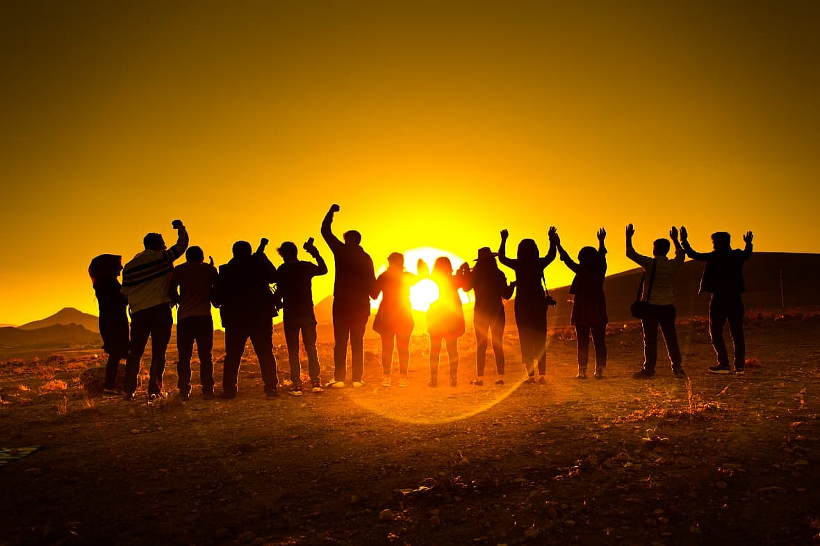 A group of people in front of a setting sun