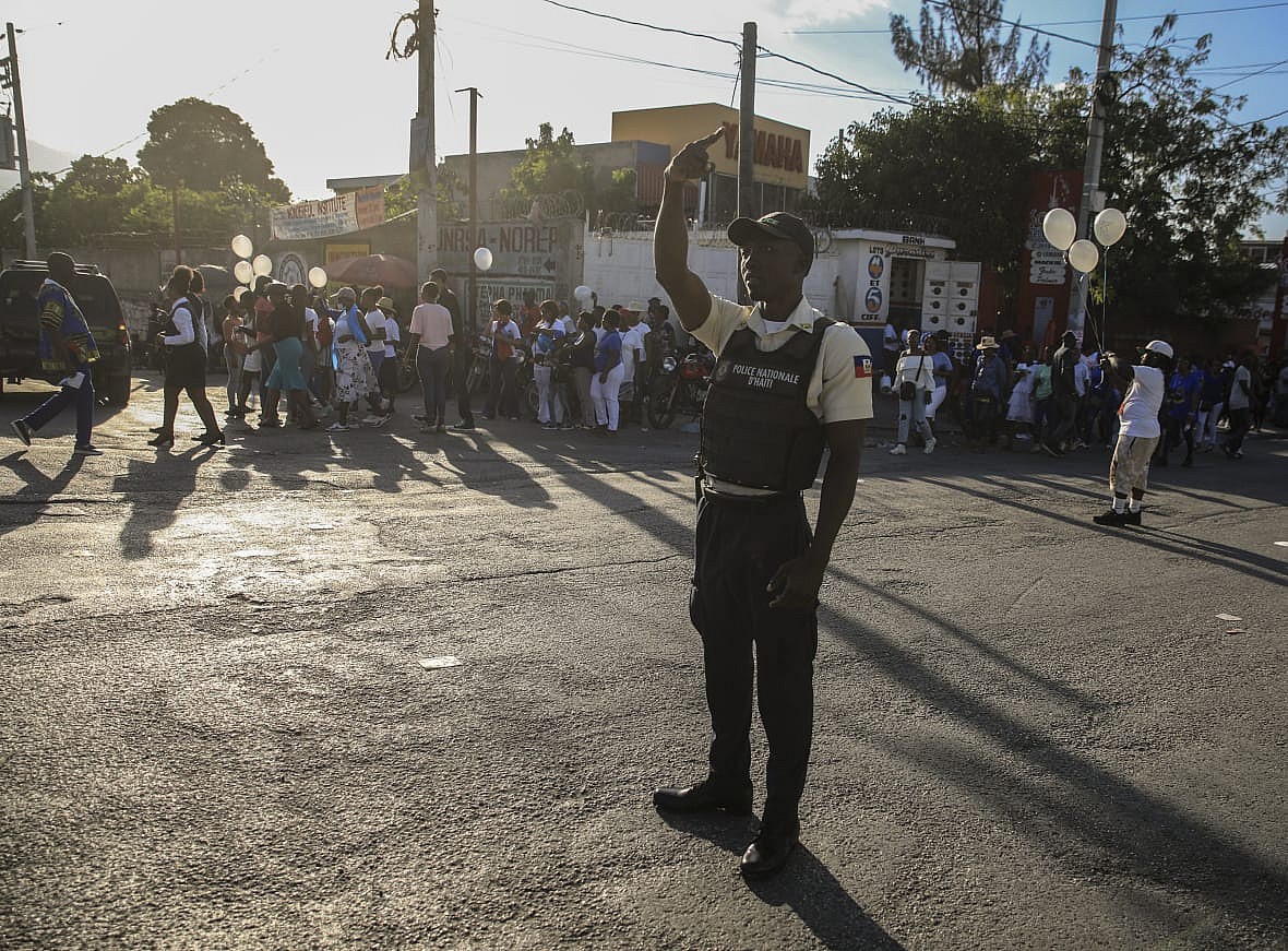 A national police officer raises his hand on a street in Haiti